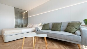A modern bedroom with a bed, grey sofa, and a small white table. - Romantic loft sea views 8km from Port Aventura (La Pineda)