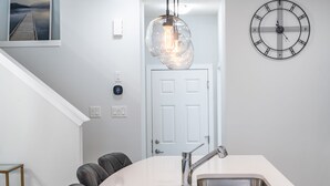 A modern kitchen with a round island, stainless steel sink, and pendant lighting.