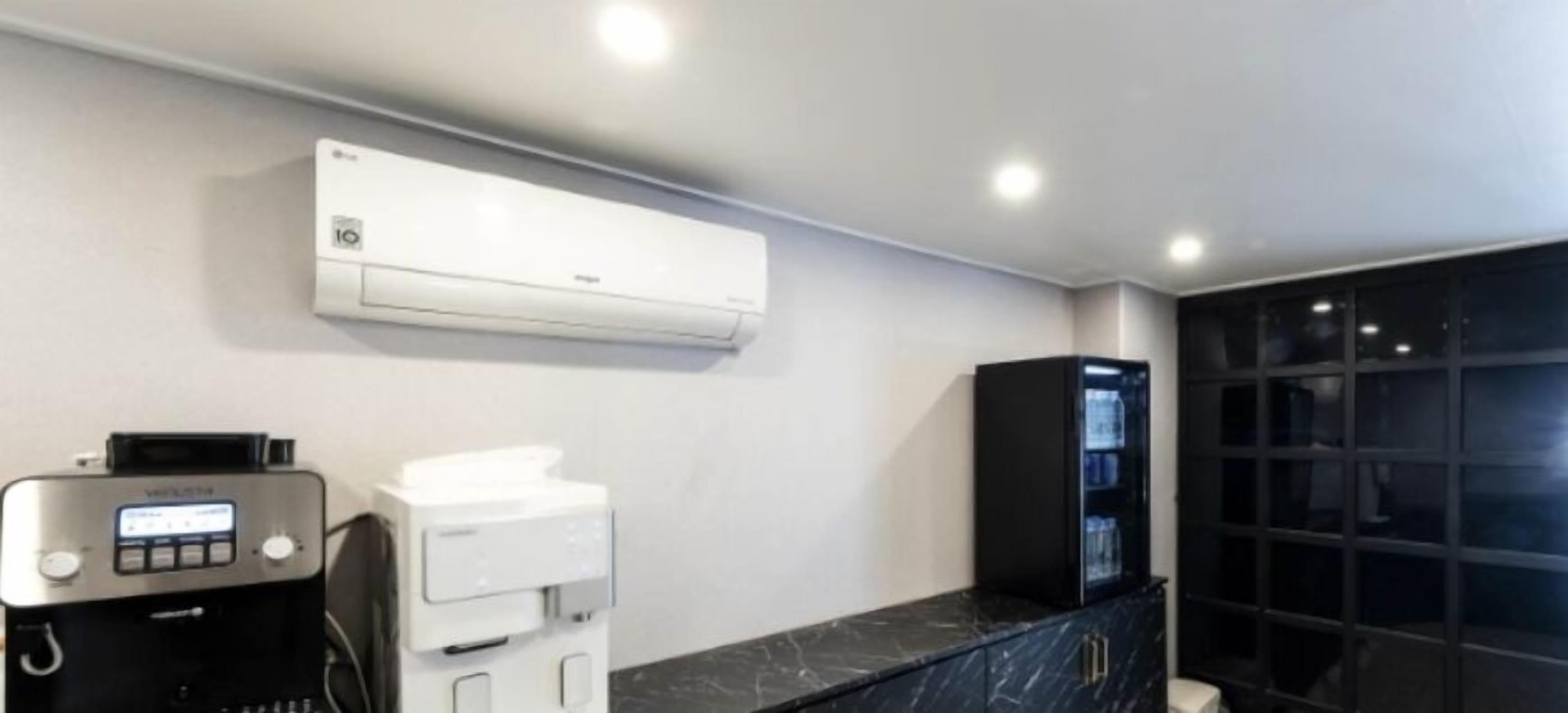A modern bathroom with a built-in air conditioner, a black marble countertop, and a black cabinet with glass doors.
