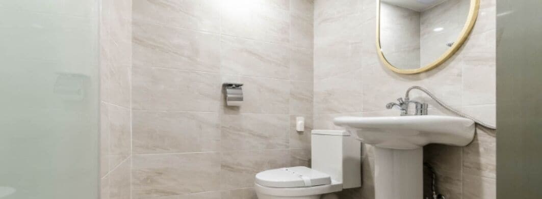 A bathroom with a toilet, sink, and mirror.