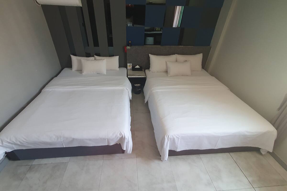 A twin room with two beds, a nightstand, and a wall-mounted shelf.