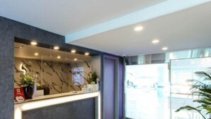 A reception area with a marble counter, a staircase, and a glass door leading outside. - Hotel ONO (Incheon)
