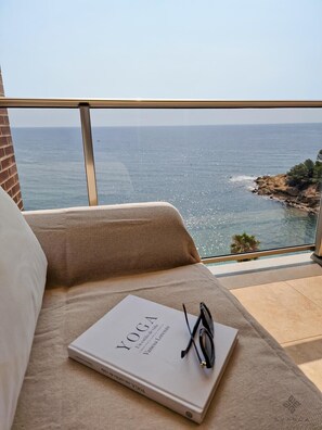 A balcony with a view of the sea, a book titled 'YOGA', and a pair of glasses on a cushion. - Beachfront flat with parking. (Calpe)