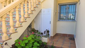Un escalier avec des balustrades, une porte blanche et une fenêtre avec des barreaux.