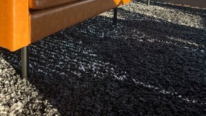 Ein braunes Ledersofa mit Kissen vor einem Fenster mit Bergblick.