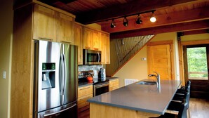 Cocina moderna con armarios de madera, electrodomésticos de acero inoxidable, una isla grande y vistas al exterior.