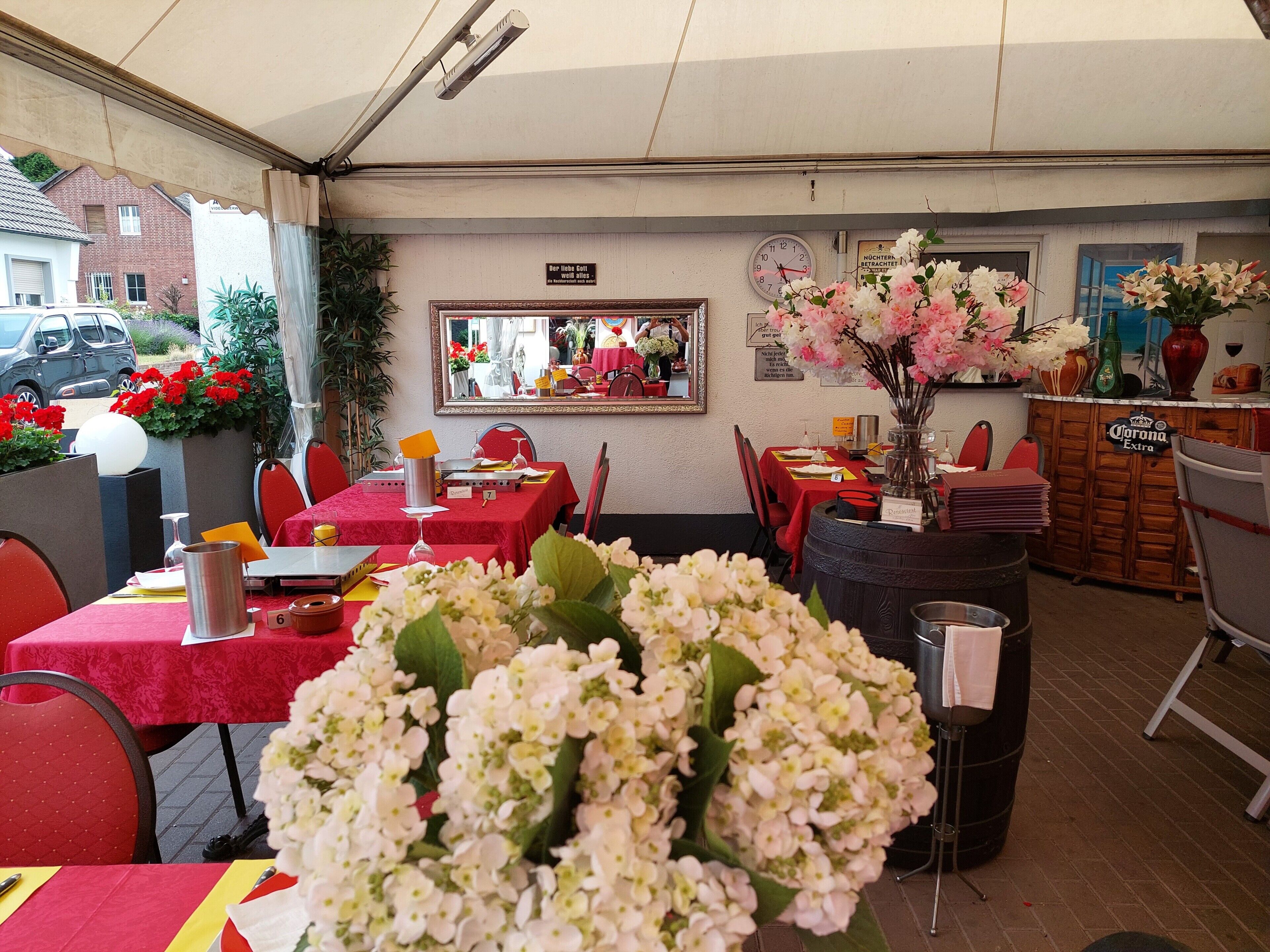 Un comedor interior con mesas dispuestas para el servicio, un reloj en la pared y una zona de bar con un cartel de Corona Extra.