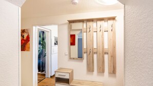 Een gang met een houten bank, een spiegel en een deur naar een andere kamer.