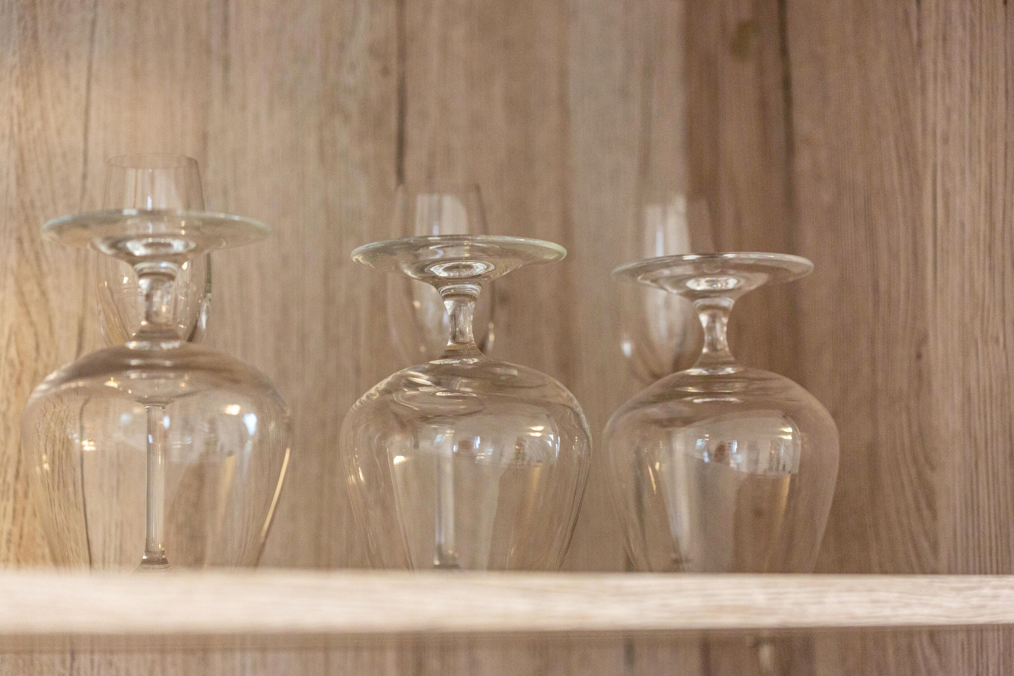 Trois bouteilles en verre transparent, posées sur une étagère devant un fond en bois.