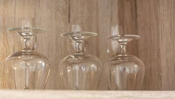 Trois bouteilles en verre transparent, posées sur une étagère devant un fond en bois.