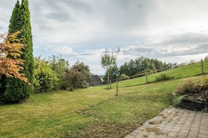 Un espace extérieur verdoyant, avec un chemin pavé, des arbres et un bâtiment situé au loin.