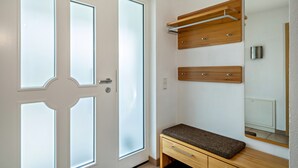 A room with a white door with frosted glass panels, a wooden bench with drawers, and a mirror on the wall. - Holiday Home 'Storchennest' with Private Terrace, Private Garden and Wi-Fi (Markdorf)