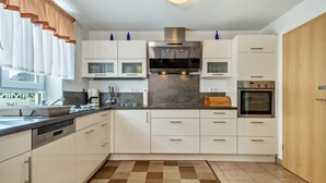 A modern kitchen with white cabinets, stainless steel appliances, and a checkered floor mat. - Holiday Home 'Storchennest' with Private Terrace, Private Garden and Wi-Fi (Markdorf)