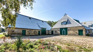 A building with a stone facade, green doors, and a sloped roof.