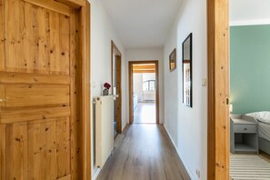 Un pasillo con puertas de madera, un radiador, cuadros enmarcados y una cama en la habitación.