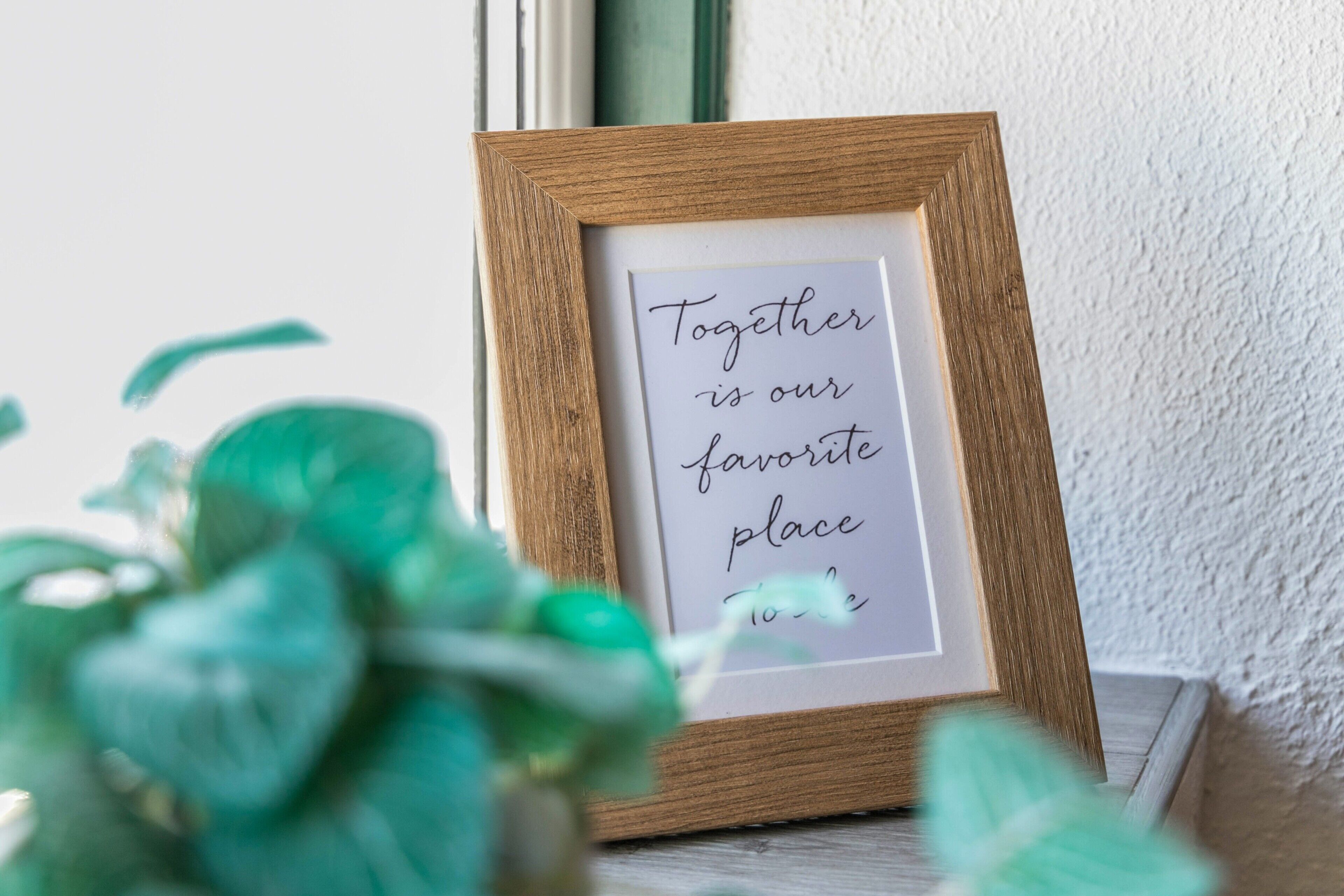 A framed sign with the text 'Together is our favorite place to be' in a wooden frame.
