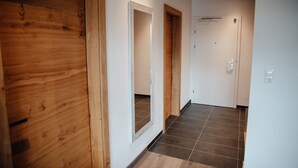 A hallway with wooden walls, a tiled floor, and a door with a white frame. - Chalet 'Zillertal Juwel' with Mountain View, Balcony and Wi-Fi (Fügen)