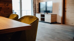 A room with a wooden table, two yellow chairs, a television on a cabinet, and a large window. - Chalet 'Zillertal Juwel' with Mountain View, Balcony and Wi-Fi (Fügen)