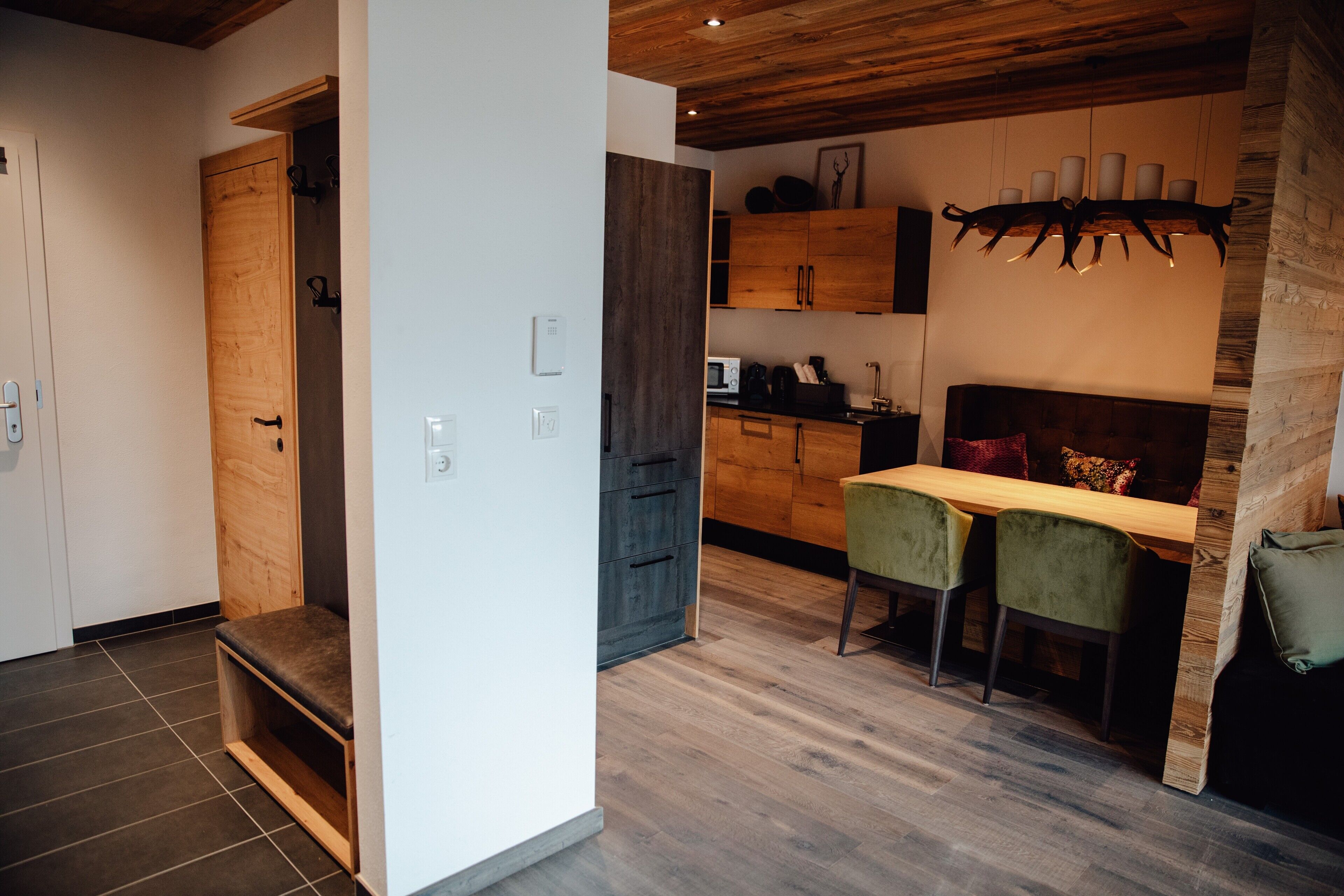 Une cuisine moderne avec des meubles en bois, un coin repas comprenant une table en bois et deux chaises, ainsi qu’un banc intégré.