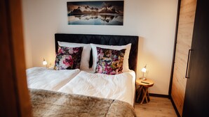 A bedroom with a bed, pillows, a nightstand, a lamp, and a painting on the wall. - Chalet 'Zillertal Juwel' with Mountain View, Balcony and Wi-Fi (Fügen)