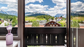 Ein Balkon mit Blick auf eine Berglandschaft, einem Holgitter und einem violetten Gegenstand an der Fensterbank.
