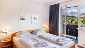 Ein Hotelzimmer mit zwei Betten, einem Fenster mit Blick auf die Berge und Bildern an der Wand.
