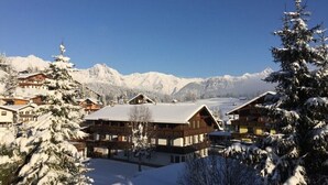 Ein verschneites Bergdorf mit Holzhäusern und wolkenlosem, blauem Himmel.