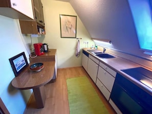 Une cuisine de taille réduite avec une table en bois, un évier et une cuisinière.