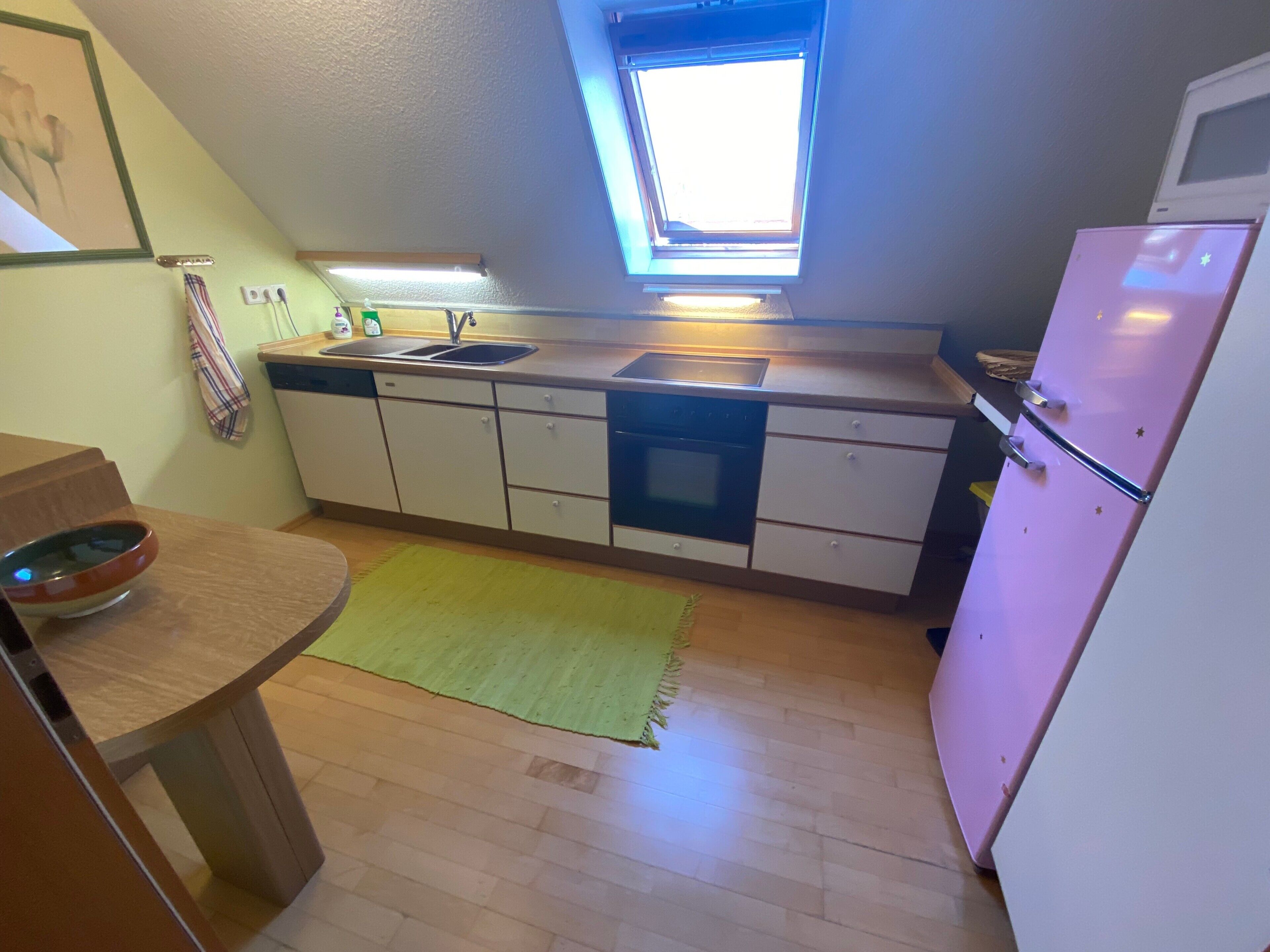 Eine kleine Küche mit Fenster, Spüle, Herd und Kühlschrank.