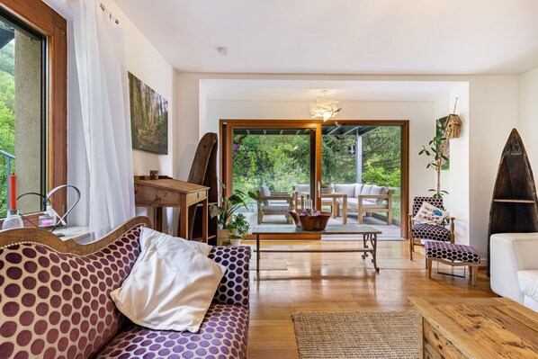 A modern living room with a sofa, armchair, and a dining area with a table and chairs.