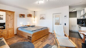 Ein Schlafzimmer mit einem hölzernen Bett, einem Schrank aus Holz, einem kleinen Nachttisch und einem Sessel.