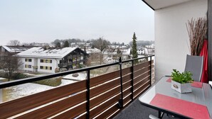 Ein Balkon mit Blick auf Gebäude und eine verschneite Landschaft.