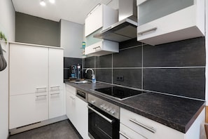 Een moderne keuken met witte kasten, een zwart aanrecht en een ingebouwde oven.