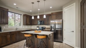 Una cocina moderna con armarios de madera oscura, electrodomésticos de acero inoxidable y una isla central con taburetes.