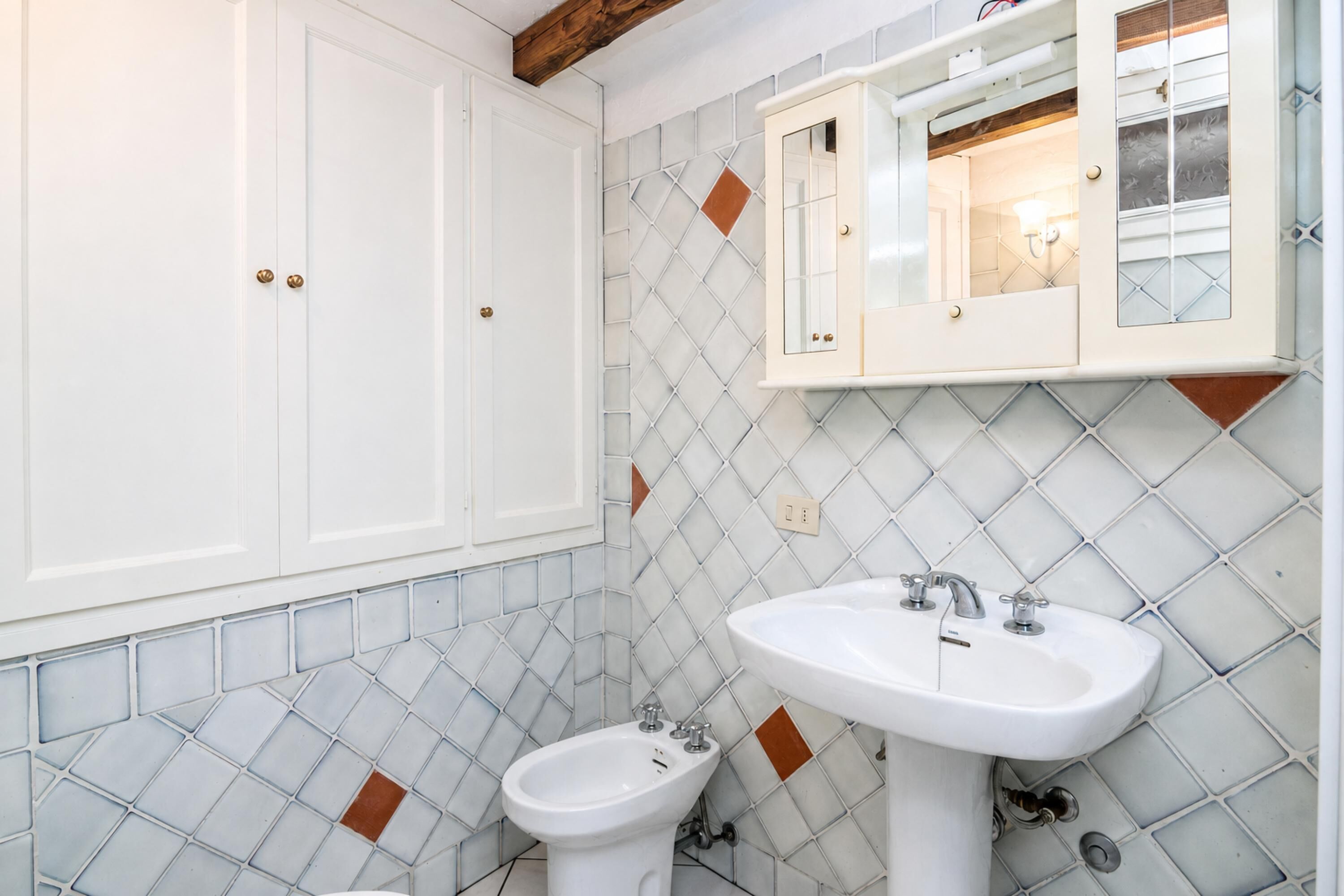 A bathroom with a white vanity, a bidet, and a sink.
