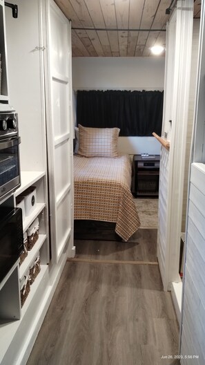Un dormitorio pequeño con cama, mesita de noche, cómoda y horno empotrado.