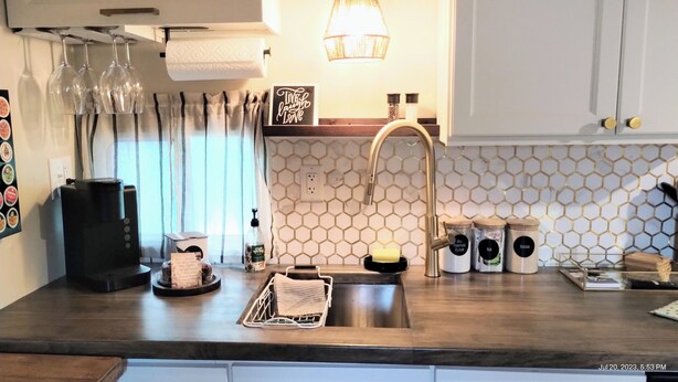 Una cocina moderna con un lavamanos de acero inoxidable, una cafetera y un salpicadero tipo panal.