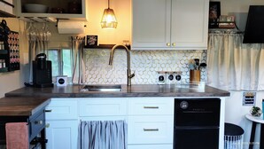 Una cocina moderna con armarios blancos, un lavamanos de acero inoxidable y un salpicadero tipo panal.