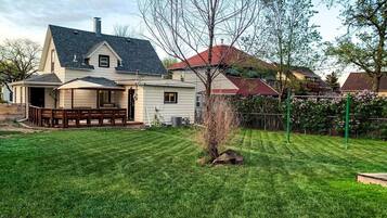 A house with a covered porch, a well-maintained lawn, and a small tree.