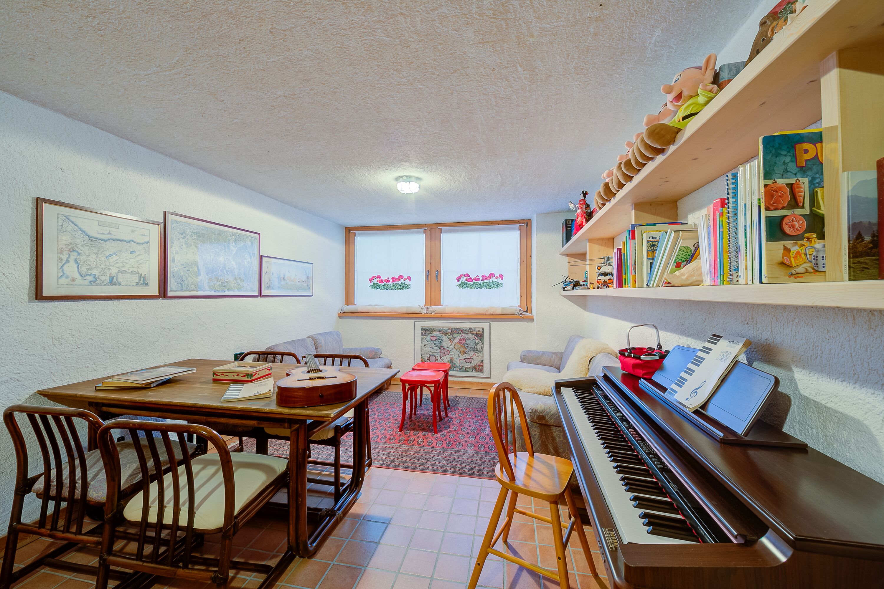 A cozy living room with a piano, a dining table with chairs, a bookshelf, and a window with curtains.