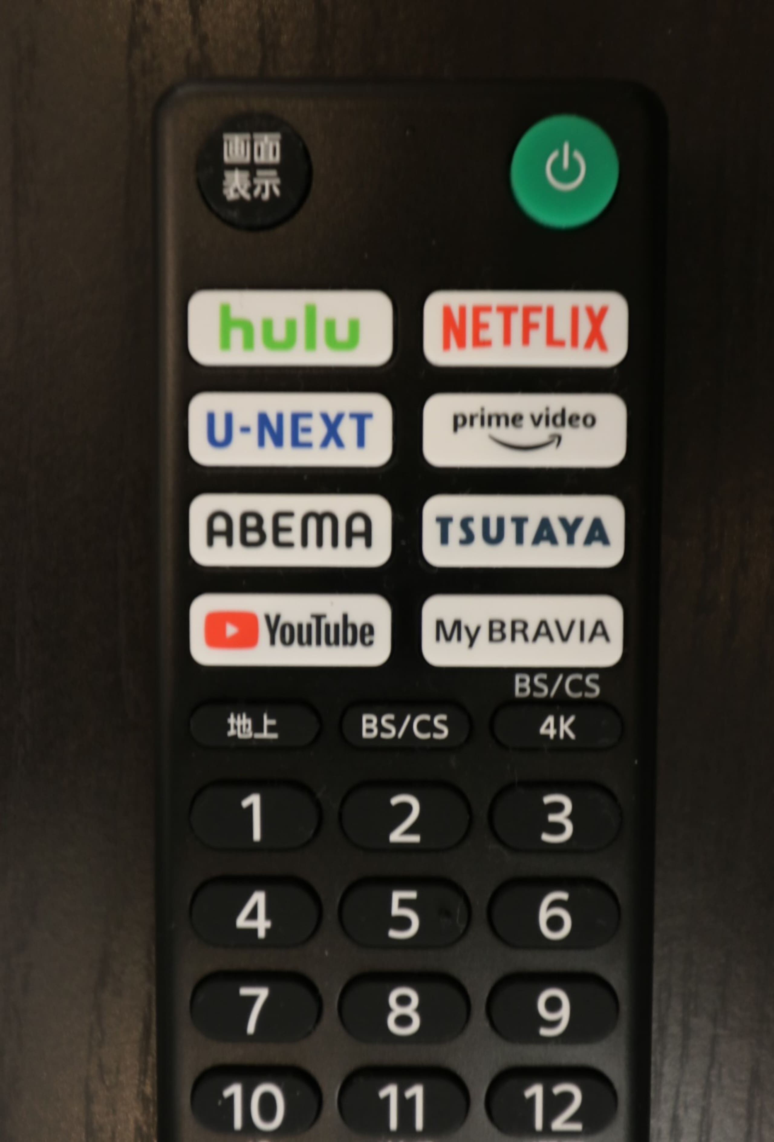 A remote control with various app icons including Hulu, Netflix, U-NEXT, and YouTube.