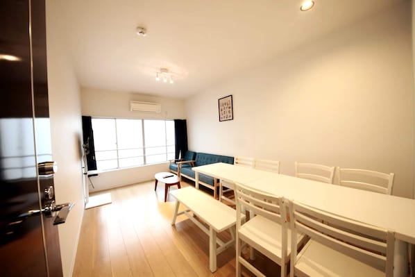 Una habitación con una mesa de comedor, sillas, un banco, un sofá y una ventana con cortinas.