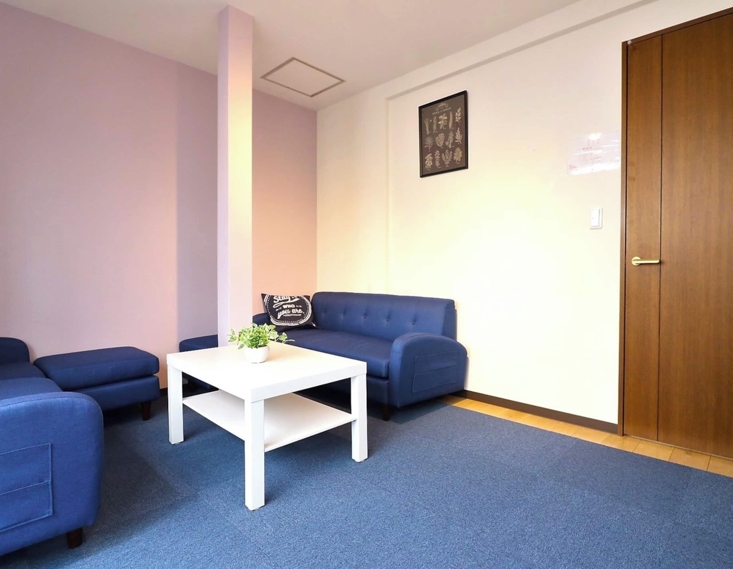 A room with a blue sofa set, a white coffee table, and a door.