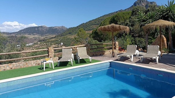 A pool with lounge chairs and a view of a mountain.