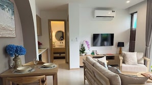 A modern living room with a sofa, a TV, and a dining area with a table and chairs. - Minh Anh Hotel (Phu Quoc)