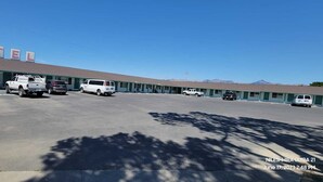 A motel with a row of rooms, a parking lot, and a mountainous backdrop. - Wiebe Motel (Hollister)