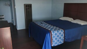 A room with a bed, a desk, and a door. - Wiebe Motel (Hollister)