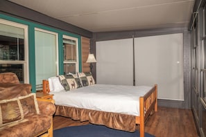 A bedroom with a bed, a chair, a lamp, and a wardrobe. - Waterfront Cabin with Private Lake Access & Fire Pit (Lac du Flambeau)