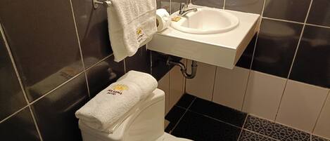 Een badkamer met toilet, wastafel en betegelde wanden.