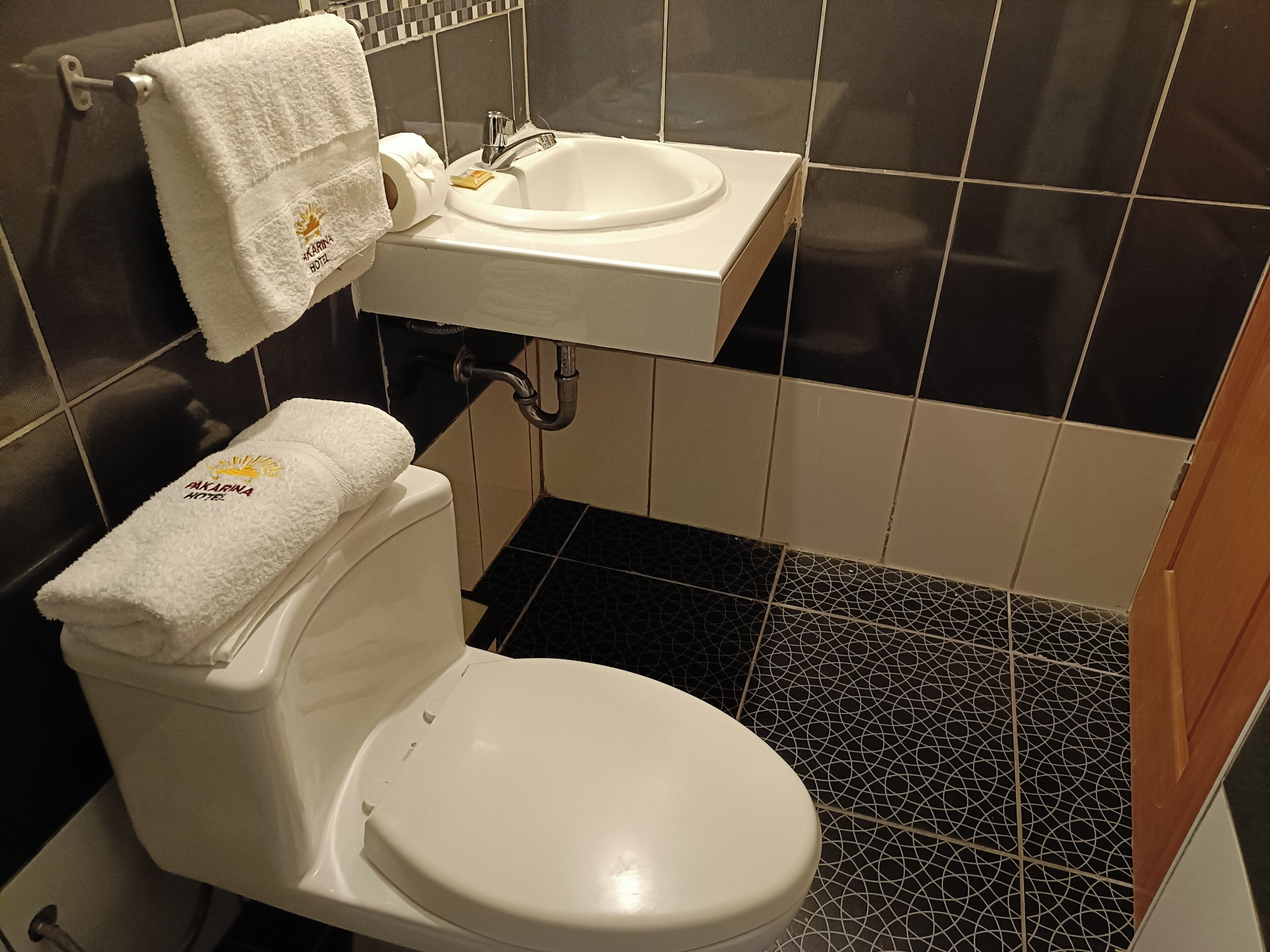 A bathroom with a white toilet, a sink, and a towel rack with a towel hanging on it.